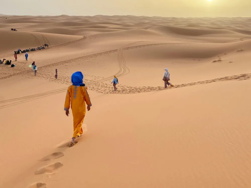 Travelers walking in the Erg Chebbi dunes on a 3-day desert tour from Fes to Merzouga